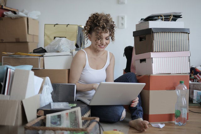 A woman sitting on the floor, surrounded with boxes.